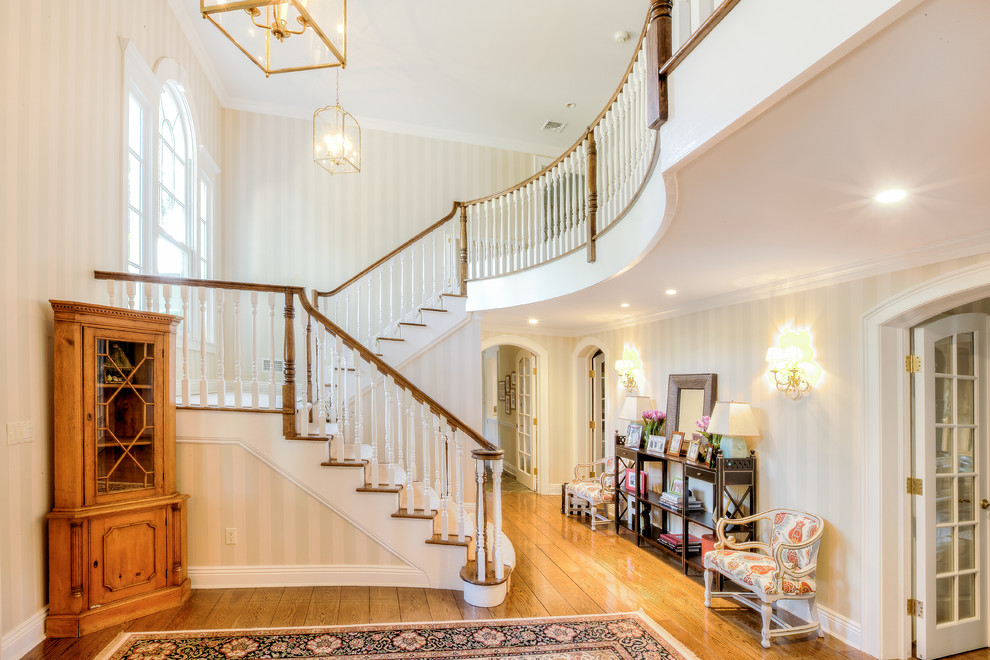 Large traditional wood u-shaped staircase in New York with painted wood risers.
