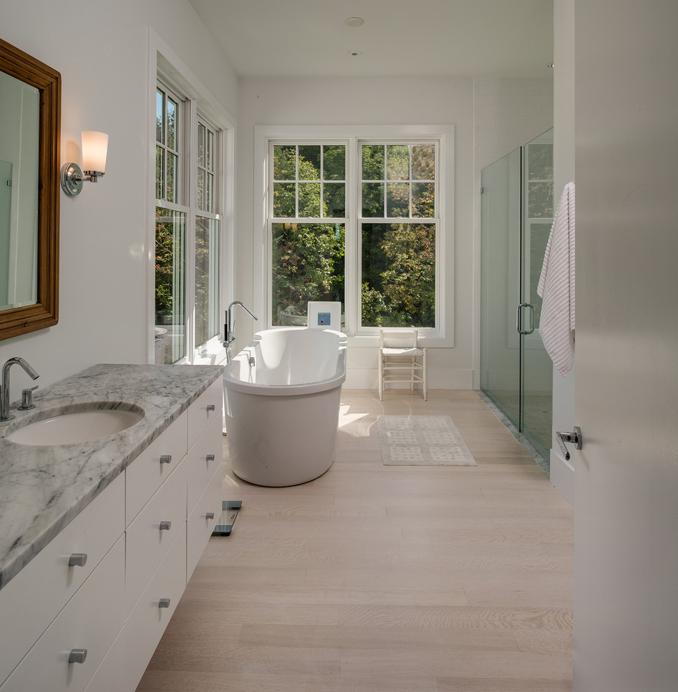 Photo of a mid-sized scandinavian master bathroom in Other with flat-panel cabinets, white cabinets, a freestanding tub, an alcove shower, multi-coloured tile, stone tile, white walls, laminate floors, an undermount sink and engineered quartz benchtops.