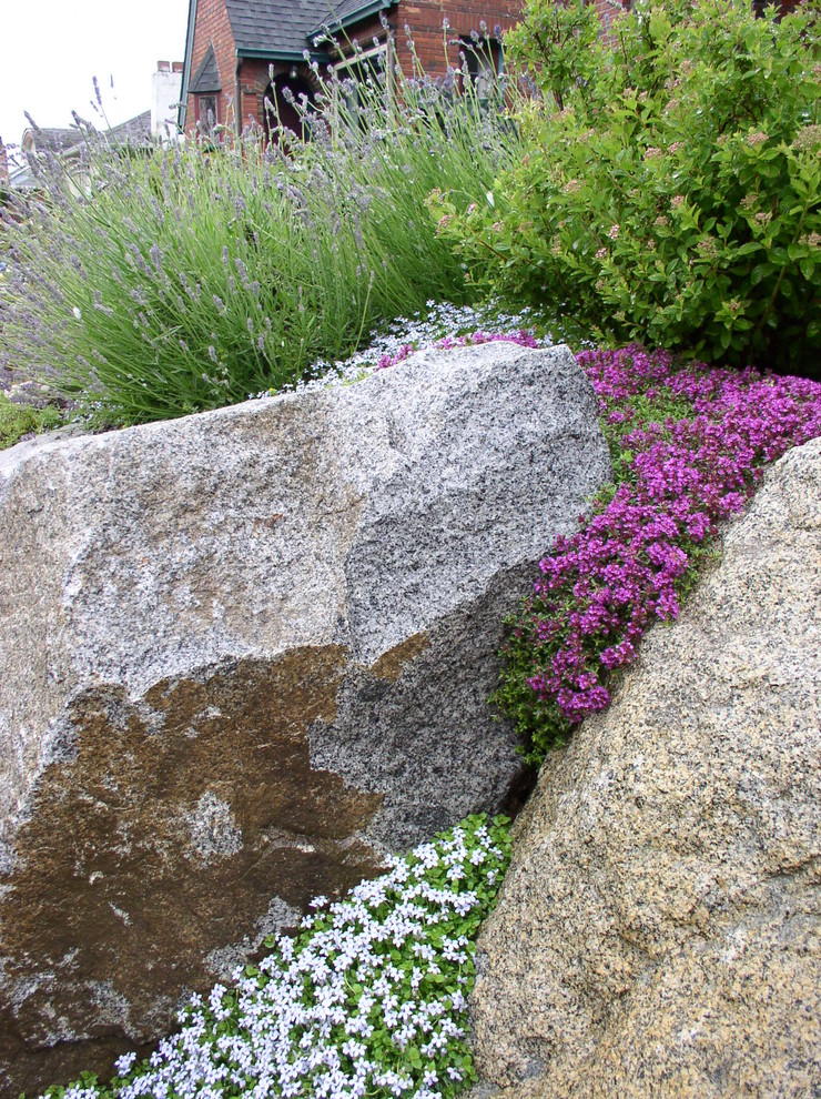 Inspiration for a mid-sized modern backyard partial sun xeriscape in Seattle with a retaining wall and natural stone pavers.
