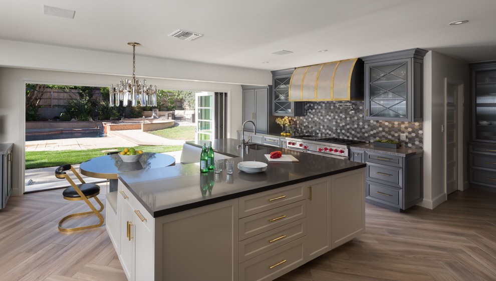 This is an example of a large transitional single-wall eat-in kitchen in Los Angeles with an undermount sink, multi-coloured splashback, porcelain splashback, panelled appliances, porcelain floors, brown floor, recessed-panel cabinets, grey cabinets, with island and grey benchtop.