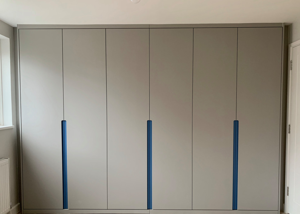 Medium sized modern built-in wardrobe in London with flat-panel cabinets.