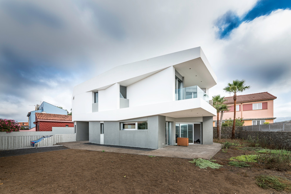 Mid-sized contemporary two-storey stucco white exterior in Other with a flat roof.