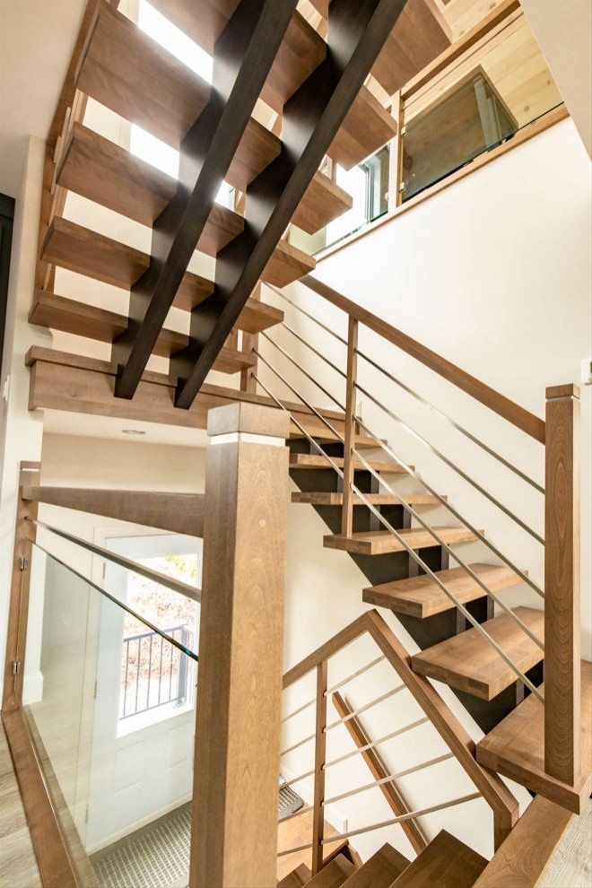 На фото: большая п-образная деревянная лестница в скандинавском стиле с деревянными ступенями и перилами из смешанных материалов с