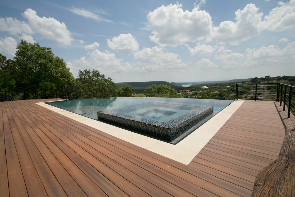 Photo of a large contemporary backyard rectangular infinity pool in Austin with a hot tub and decking.