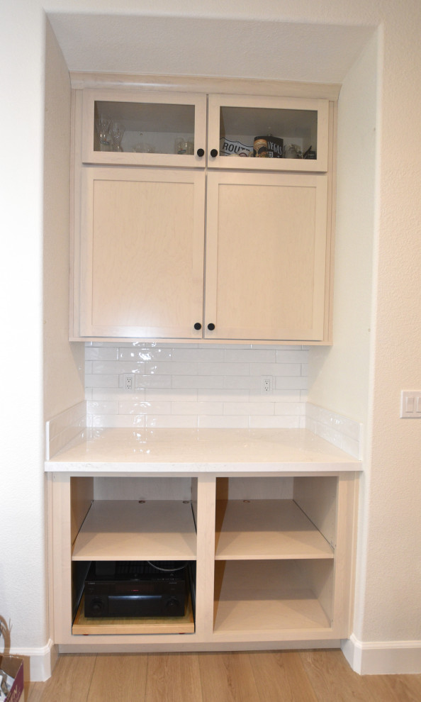 Large transitional l-shaped vinyl floor and beige floor kitchen photo with an undermount sink, shaker cabinets, light wood cabinets, solid surface countertops, white backsplash, porcelain backsplash, stainless steel appliances, an island and white countertops