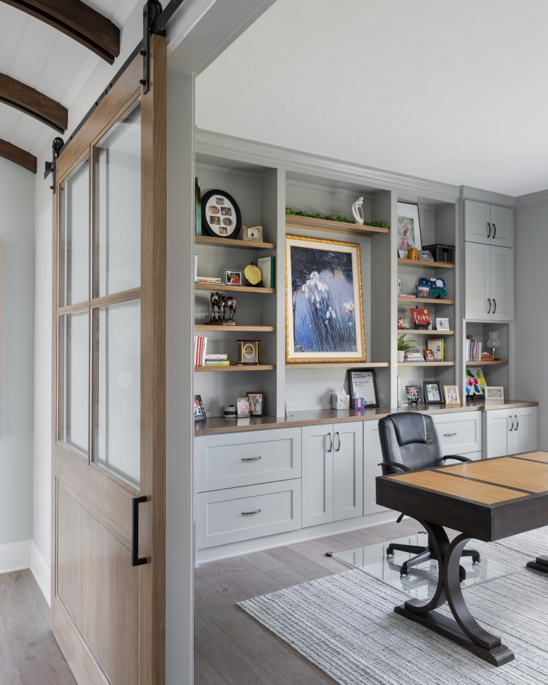 Modelo de despacho tradicional renovado de tamaño medio sin chimenea con paredes multicolor, suelo de madera oscura y escritorio independiente