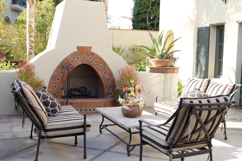 Design ideas for a mid-sized mediterranean courtyard patio in San Diego with concrete slab, no cover and with fireplace.