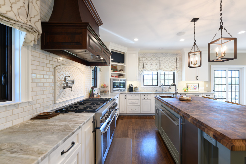 Inspiration for a large transitional l-shaped dark wood floor and brown floor kitchen remodel with an undermount sink, raised-panel cabinets, white cabinets, quartzite countertops, white backsplash, marble backsplash, stainless steel appliances and an island