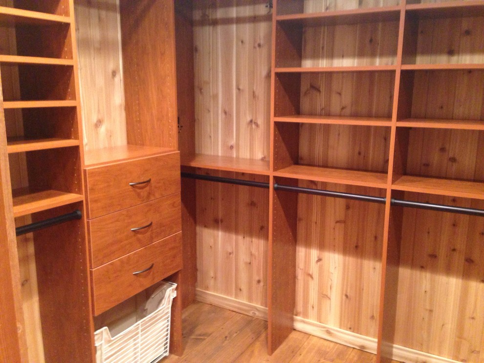 This is an example of a large traditional gender-neutral walk-in wardrobe in Other with flat-panel cabinets, medium wood cabinets and medium hardwood floors.