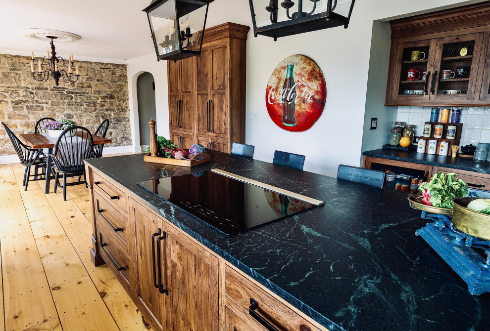 На фото: кухня в стиле кантри с темными деревянными фасадами и столешницей из талькохлорита с