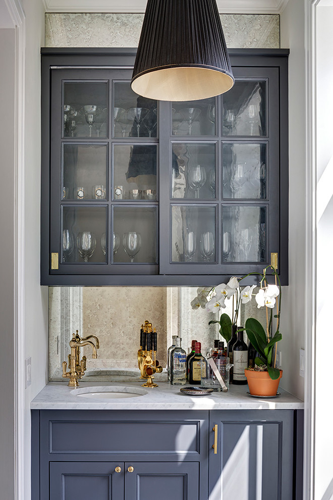 Design ideas for a traditional home bar in New York with glass-front cabinets and blue cabinets.