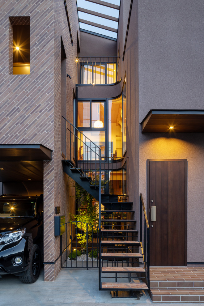 Large modern brown three-story brick house exterior idea in Tokyo with a black roof