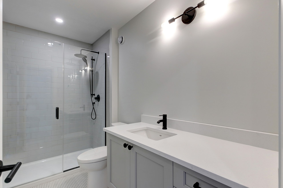 Mid-sized transitional kids' cement tile floor alcove shower photo in Edmonton with recessed-panel cabinets, gray walls, an undermount sink, quartz countertops, a hinged shower door, white countertops and gray cabinets