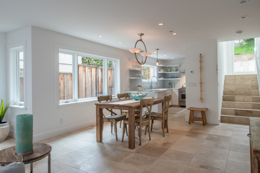This is an example of a mid-sized modern open plan dining in Other with white walls, limestone floors, a standard fireplace, a tile fireplace surround and brown floor.