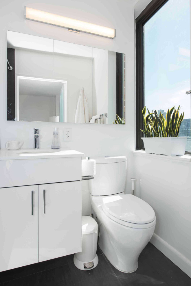 Cette photo montre une salle de bain principale moderne de taille moyenne avec un placard à porte plane, des portes de placard blanches, une baignoire posée, un combiné douche/baignoire, WC à poser, un carrelage blanc, des carreaux de céramique, un mur blanc, un sol en carrelage de porcelaine, un lavabo encastré, un plan de toilette en quartz modifié, un sol noir, une cabine de douche avec un rideau, un plan de toilette blanc, meuble simple vasque et meuble-lavabo suspendu.