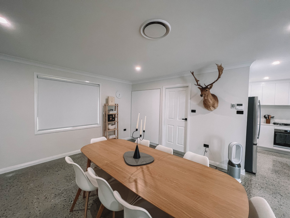 Esempio di una sala da pranzo aperta verso il soggiorno scandinava di medie dimensioni con pareti bianche, pavimento in cemento, pavimento grigio, soffitto in legno e pareti in legno