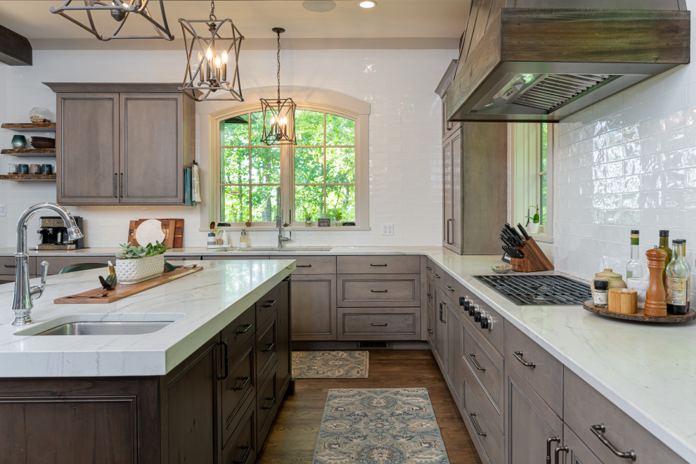 Open concept kitchen - mid-sized transitional u-shaped medium tone wood floor, brown floor and exposed beam open concept kitchen idea with an undermount sink, recessed-panel cabinets, medium tone wood cabinets, marble countertops, white backsplash, ceramic backsplash, paneled appliances, an island and multicolored countertops