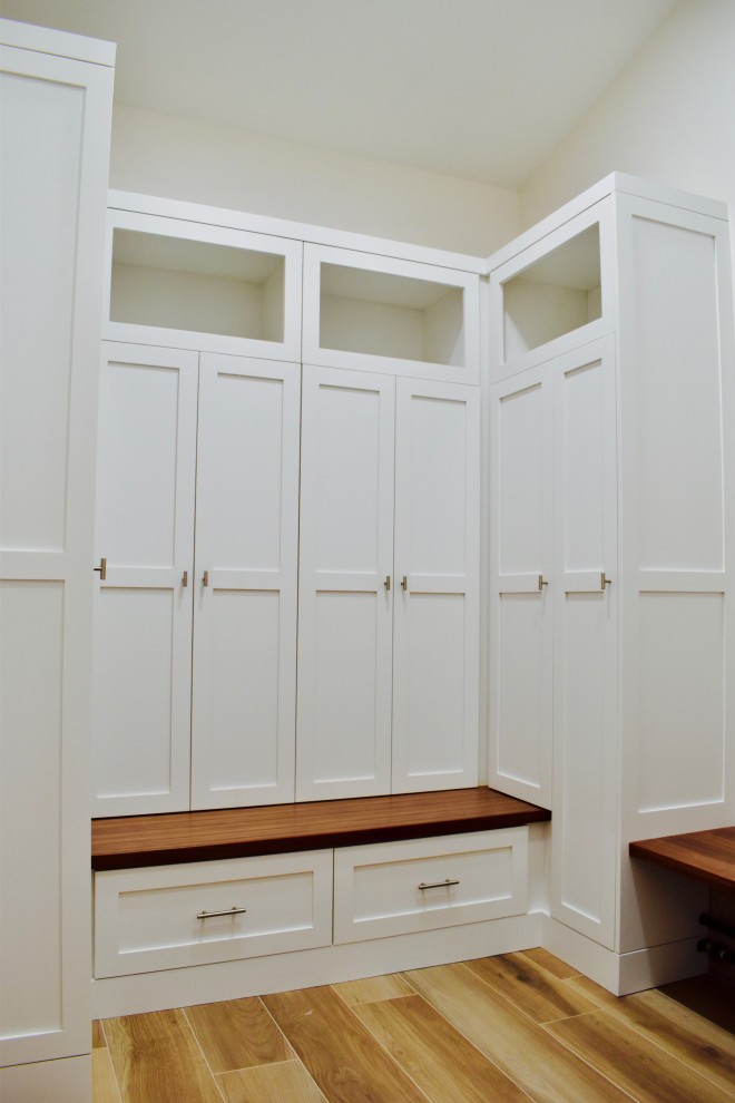 Example of a mid-sized transitional ceramic tile and brown floor mudroom design with beige walls and a white front door