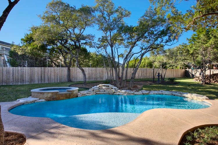 Inspiration for a large traditional backyard custom-shaped pool in Austin with a hot tub and concrete slab.