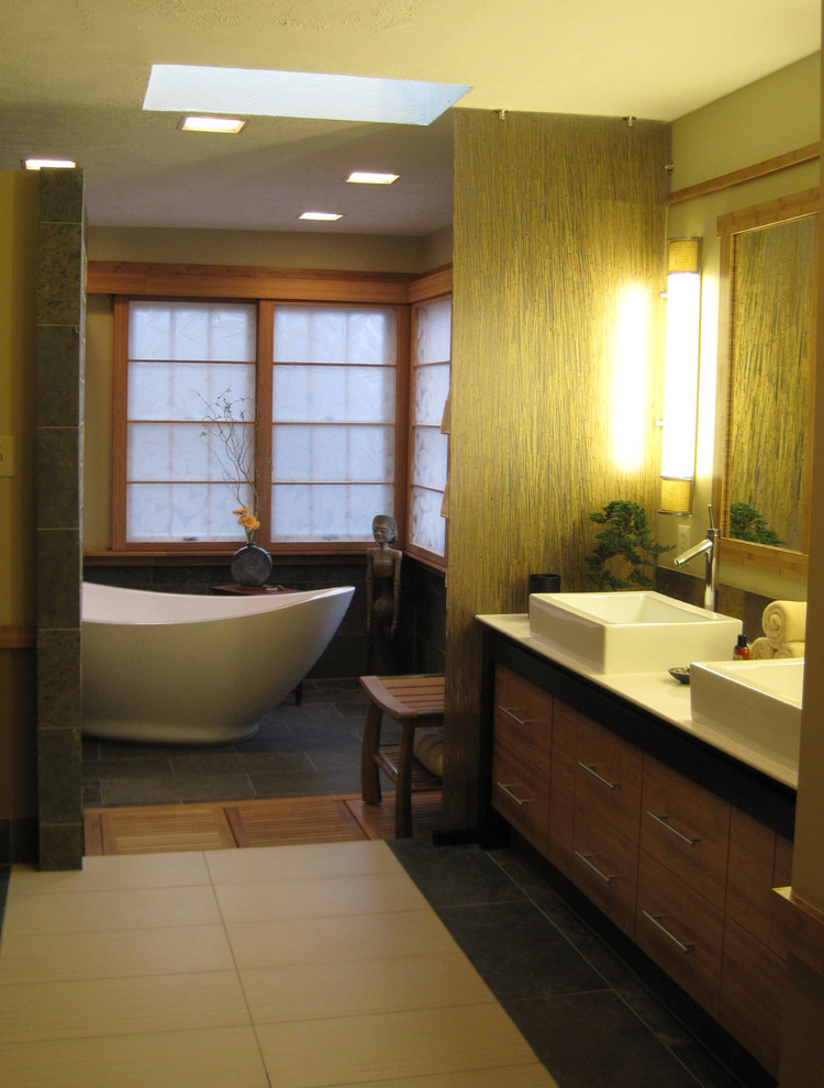 This is an example of a mid-sized asian master bathroom in DC Metro with flat-panel cabinets, medium wood cabinets, a freestanding tub, an alcove shower, stone tile, beige walls, ceramic floors, a vessel sink and quartzite benchtops.