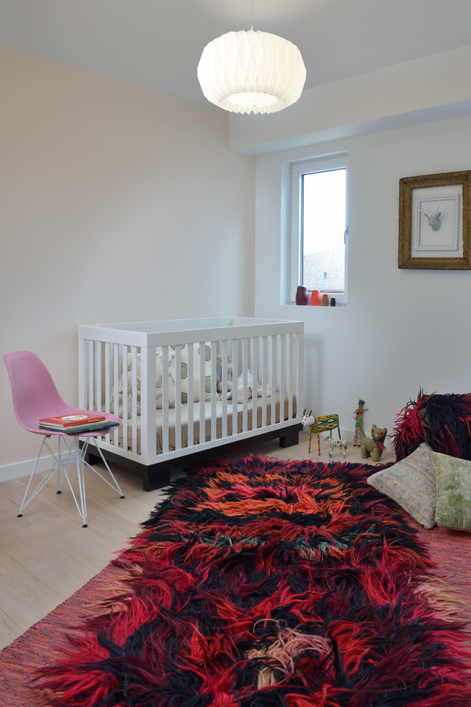 Design ideas for a mid-sized contemporary nursery for girls in Toronto with white walls, light hardwood floors and beige floor.