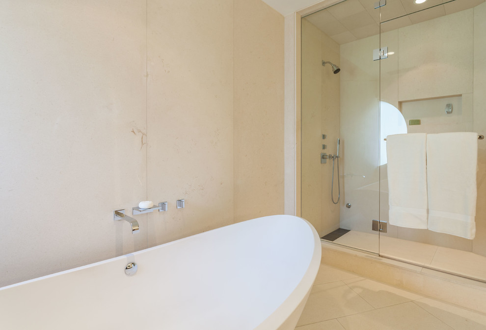 Photo of a large modern master bathroom in Vancouver with flat-panel cabinets, medium wood cabinets, a freestanding tub, an alcove shower, a one-piece toilet, beige walls, porcelain floors, an undermount sink, glass benchtops, beige floor and a hinged shower door.