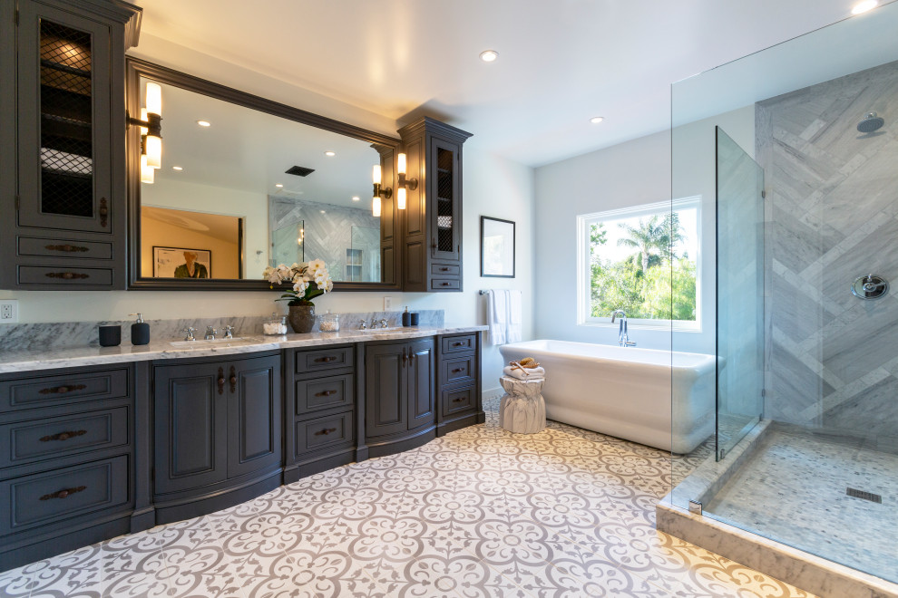 Mediterranean bathroom in Los Angeles with raised-panel cabinets, grey cabinets, a freestanding tub, a corner shower, gray tile, grey walls, an undermount sink, grey floor, an open shower, grey benchtops, a double vanity and a built-in vanity.