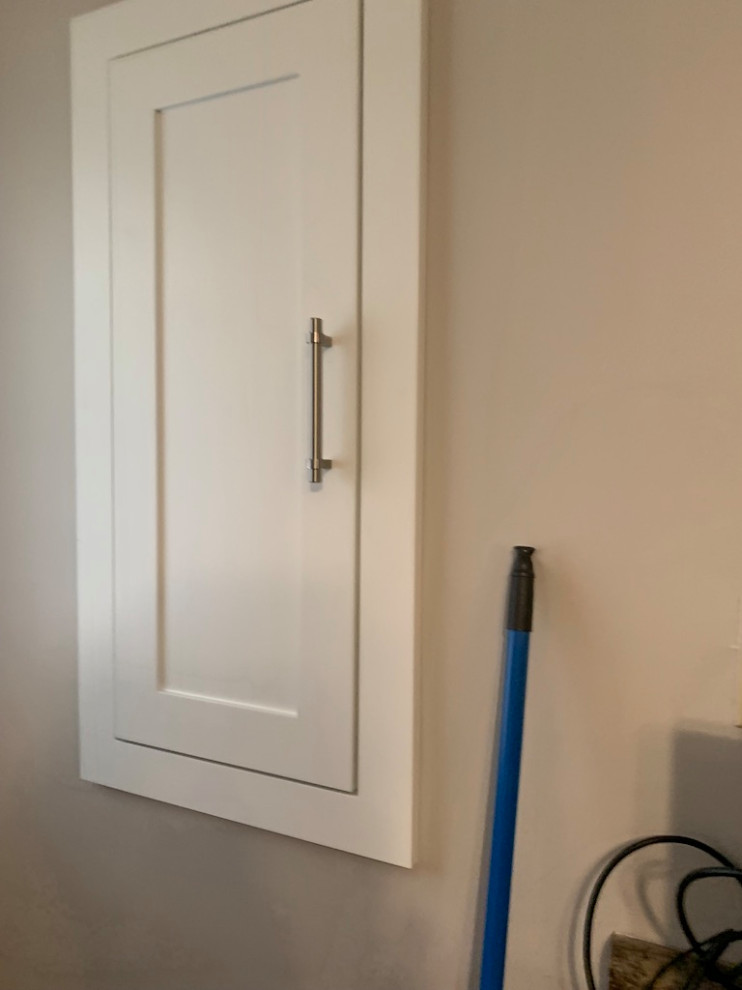 Example of a small transitional galley medium tone wood floor open concept kitchen design in Toronto with shaker cabinets, white cabinets, solid surface countertops, an island and white countertops
