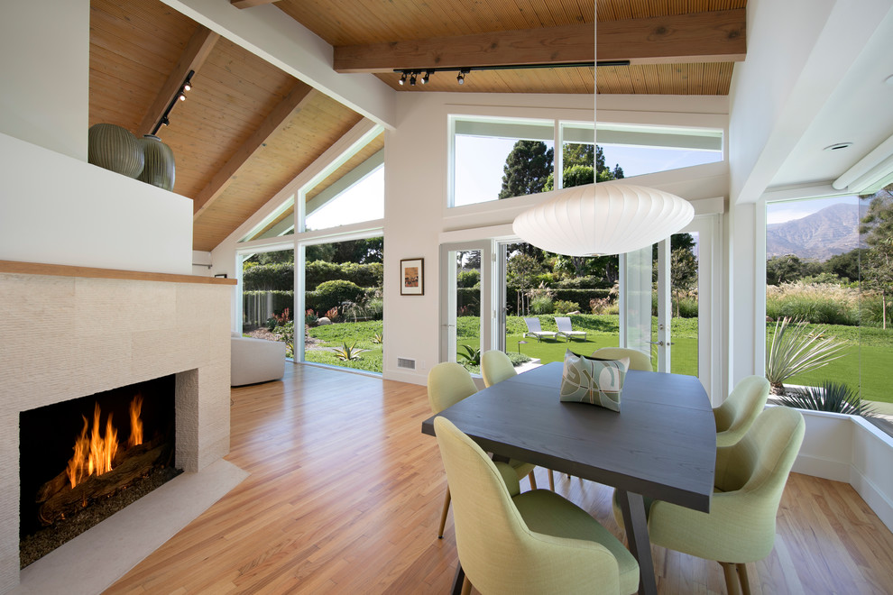 Photo of a midcentury dining room in Santa Barbara with white walls, light hardwood floors and a ribbon fireplace.