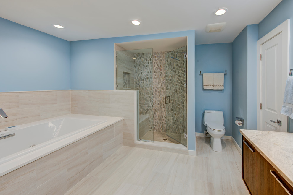 Transitional brown tile, white tile and matchstick tile porcelain tile drop-in bathtub photo with flat-panel cabinets, dark wood cabinets, a two-piece toilet, blue walls and granite countertops