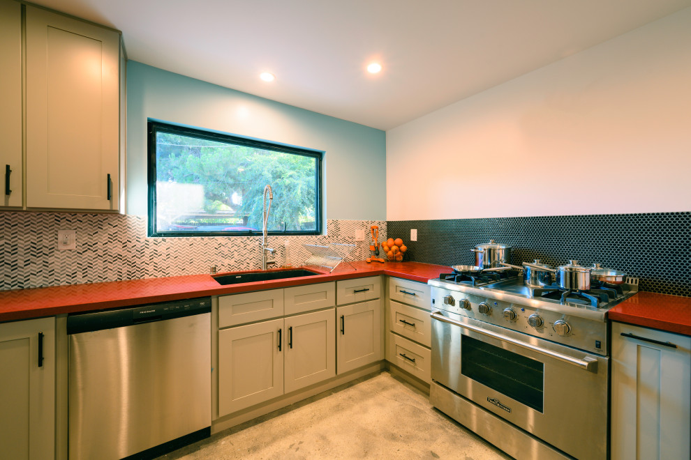 Mid-sized minimalist l-shaped gray floor and concrete floor kitchen pantry photo in Los Angeles with a double-bowl sink, shaker cabinets, beige cabinets, quartz countertops, blue backsplash, ceramic backsplash, stainless steel appliances and orange countertops