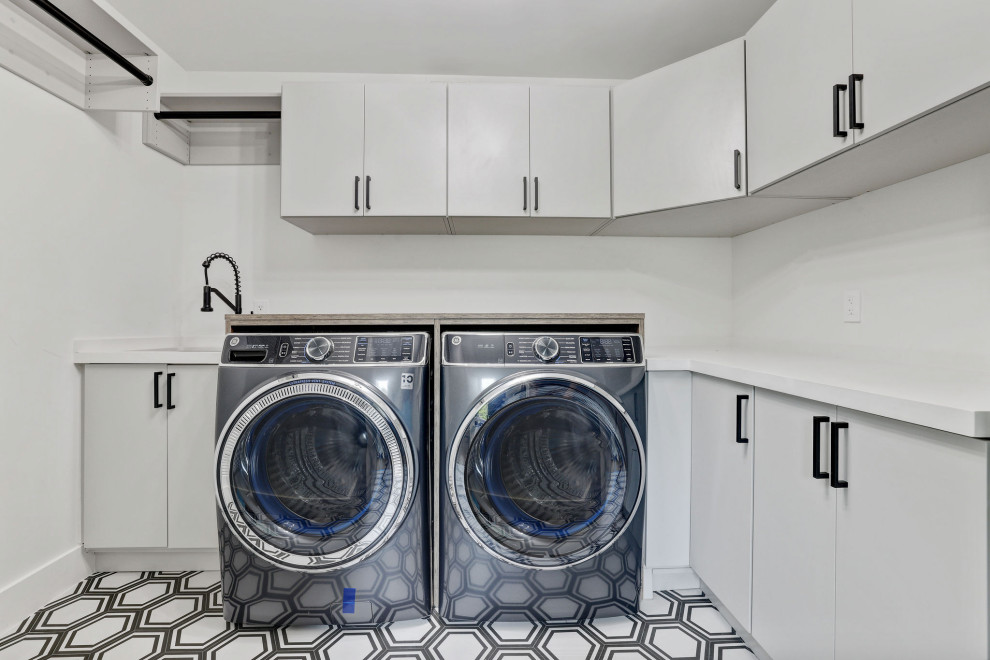 Photo of a large contemporary utility room in Miami with an undermount sink, grey cabinets, quartz benchtops, white splashback, white walls, ceramic floors, a side-by-side washer and dryer, multi-coloured floor and white benchtop.