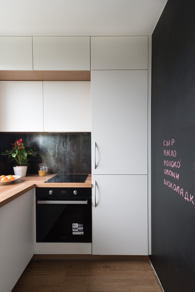 Inspiration for a small contemporary l-shaped separate kitchen in Moscow with no island, flat-panel cabinets, white cabinets, black splashback, black appliances, brown floor and brown benchtop.