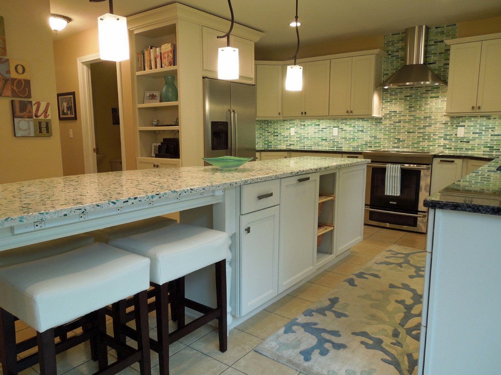 This is an example of a mid-sized beach style u-shaped open plan kitchen in Charleston with an undermount sink, recessed-panel cabinets, white cabinets, recycled glass benchtops, green splashback, glass tile splashback, stainless steel appliances, ceramic floors and with island.