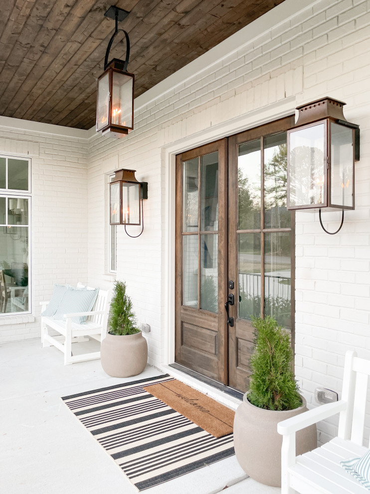 Idée de décoration pour un grand porche d'entrée de maison avant tradition avec une dalle de béton et une extension de toiture.