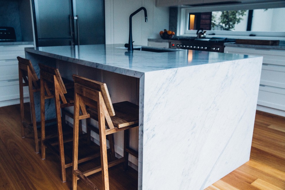 Design ideas for a contemporary l-shaped open plan kitchen in Sydney with white cabinets, marble benchtops, grey splashback, stone slab splashback, stainless steel appliances, medium hardwood floors, with island, an undermount sink and recessed-panel cabinets.