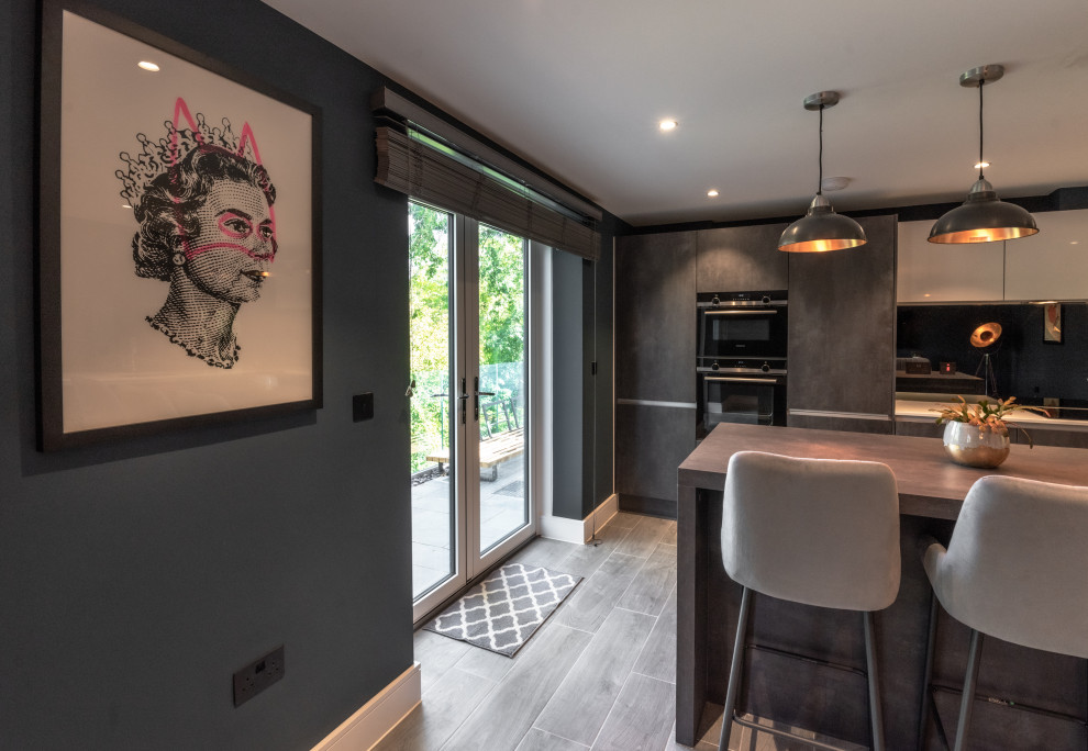 Photo of a large urban grey and black l-shaped open plan kitchen in Kent with a built-in sink, quartz worktops, metallic splashback, mirror splashback, integrated appliances, porcelain flooring, an island, grey floors, white worktops and feature lighting.