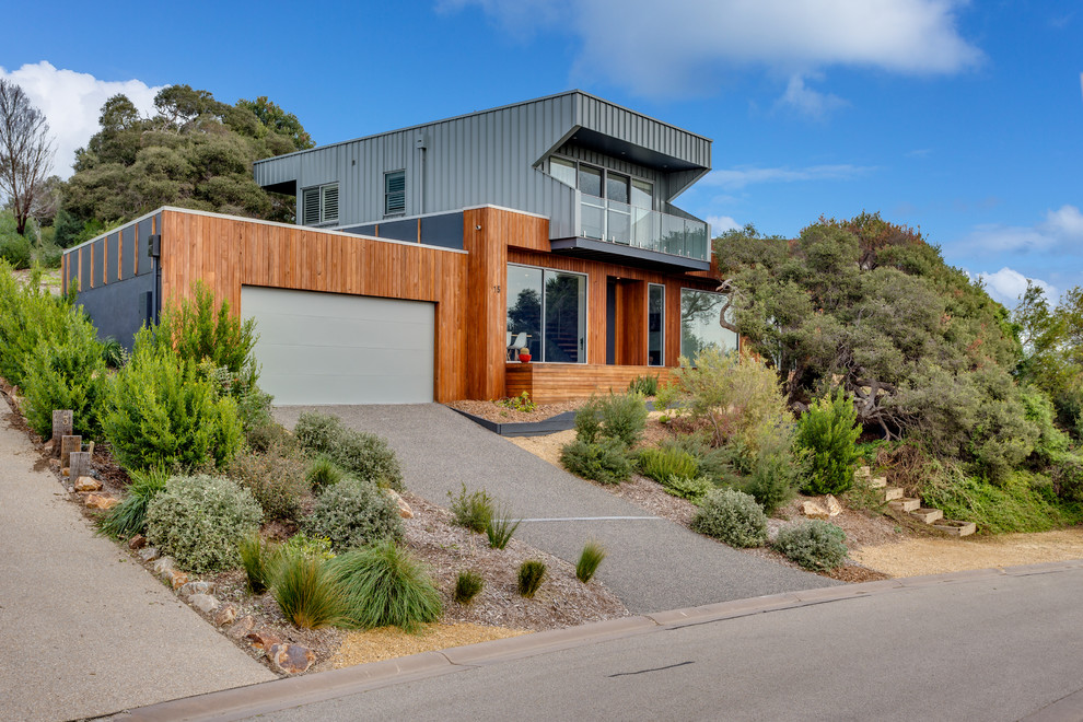 This is an example of a contemporary two-storey brown house exterior in Melbourne with mixed siding and a flat roof.