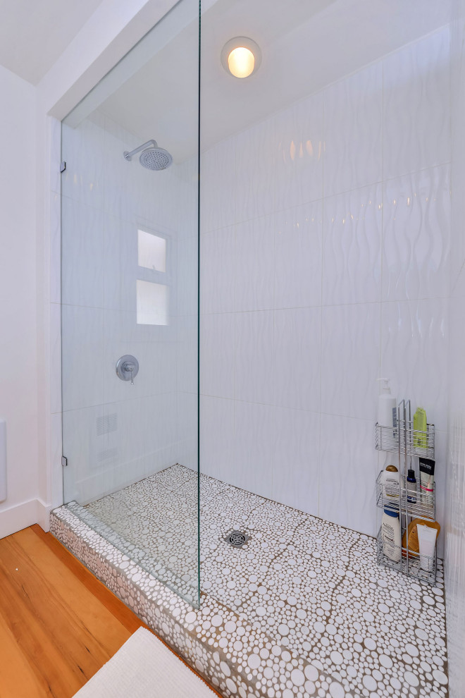 Inredning av ett 60 tals mellanstort brun brunt en-suite badrum, med en öppen dusch, en toalettstol med hel cisternkåpa, vit kakel, kakel i småsten, vita väggar, mellanmörkt trägolv, ett fristående handfat, träbänkskiva, orange golv och med dusch som är öppen