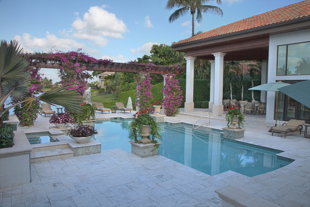 Inspiration for a large mediterranean backyard custom-shaped pool in Miami with a water feature and natural stone pavers.