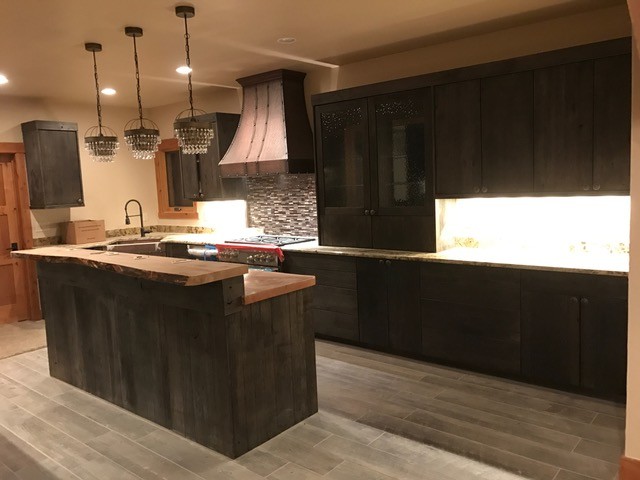 Example of a mid-sized mountain style u-shaped porcelain tile and gray floor open concept kitchen design in Denver with a farmhouse sink, recessed-panel cabinets, dark wood cabinets, wood countertops, multicolored backsplash, matchstick tile backsplash, stainless steel appliances and an island