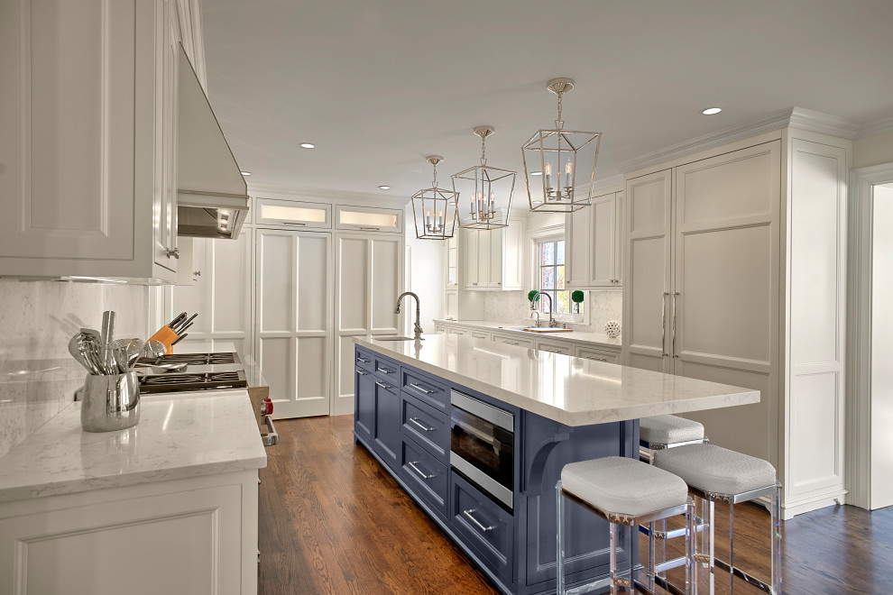 Mid-sized transitional u-shaped eat-in kitchen in Chicago with a drop-in sink, recessed-panel cabinets, white cabinets, quartz benchtops, white splashback, engineered quartz splashback, stainless steel appliances, medium hardwood floors, with island, brown floor and white benchtop.