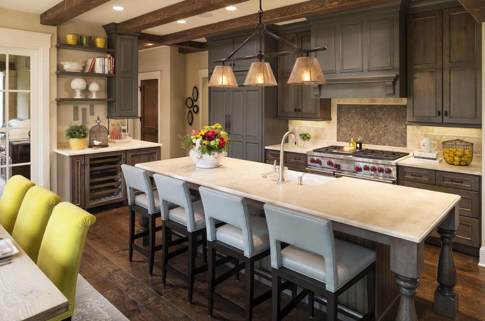 Mid-sized traditional l-shaped eat-in kitchen in Minneapolis with a farmhouse sink, recessed-panel cabinets, dark wood cabinets, limestone benchtops, stainless steel appliances, dark hardwood floors, with island, beige splashback, brown floor and limestone splashback.