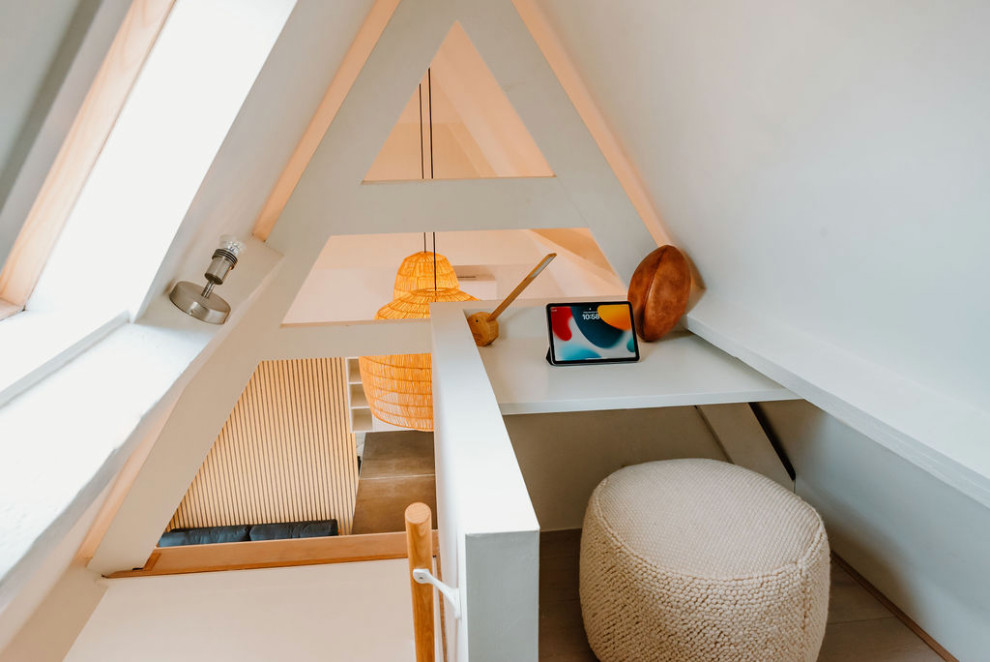 Kleines Modernes Arbeitszimmer ohne Kamin mit Arbeitsplatz, weißer Wandfarbe, hellem Holzboden, Einbau-Schreibtisch, braunem Boden und freigelegten Dachbalken in Sonstige