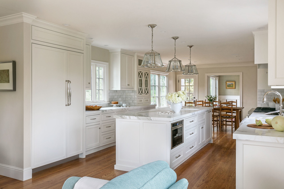 Design ideas for a traditional open plan kitchen in San Francisco with shaker cabinets, white cabinets, grey splashback, panelled appliances, medium hardwood floors, with island and white benchtop.