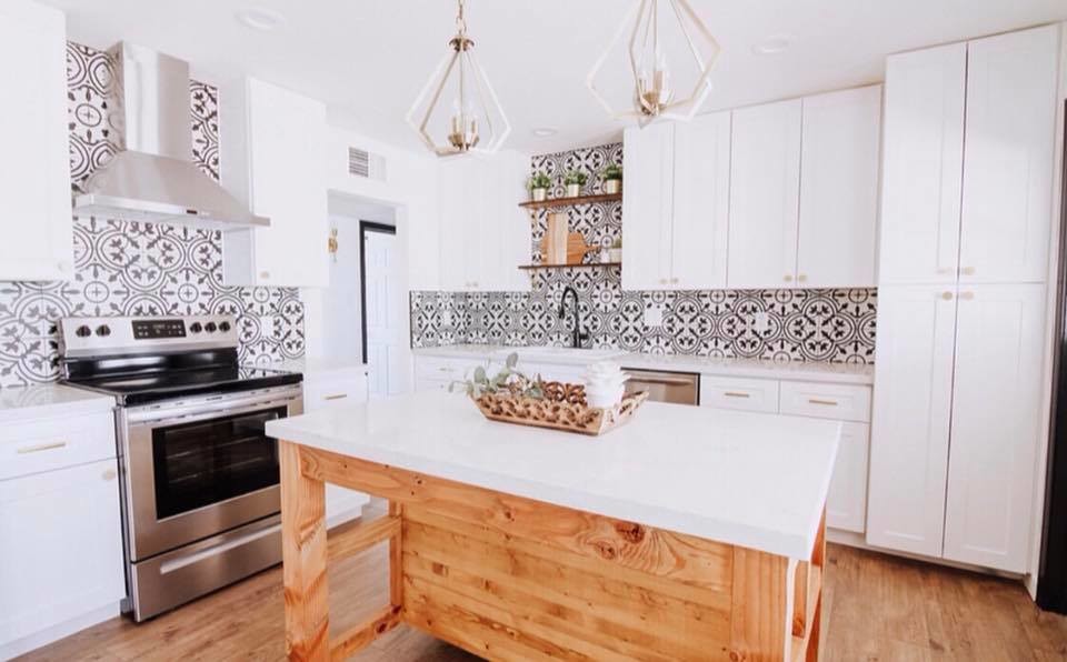Mid-sized eclectic l-shaped eat-in kitchen in Miami with a drop-in sink, shaker cabinets, white cabinets, quartzite benchtops, multi-coloured splashback, cement tile splashback, stainless steel appliances, medium hardwood floors, with island, beige floor and white benchtop.