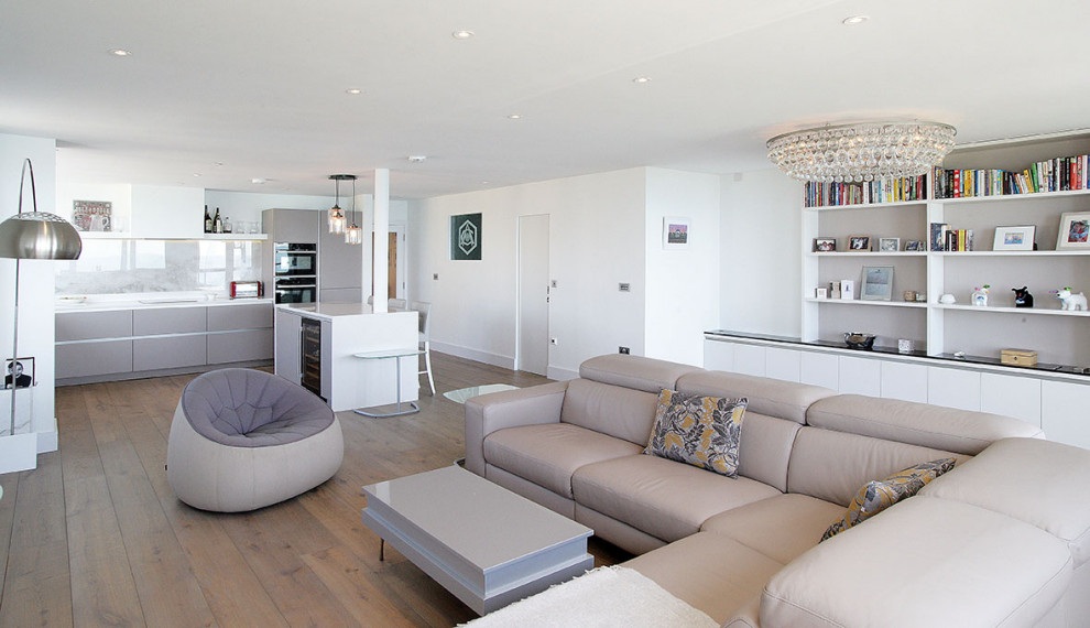 Photo of a large contemporary open concept living room in Sussex with white walls, medium hardwood floors, a wall-mounted tv, brown floor and recessed.