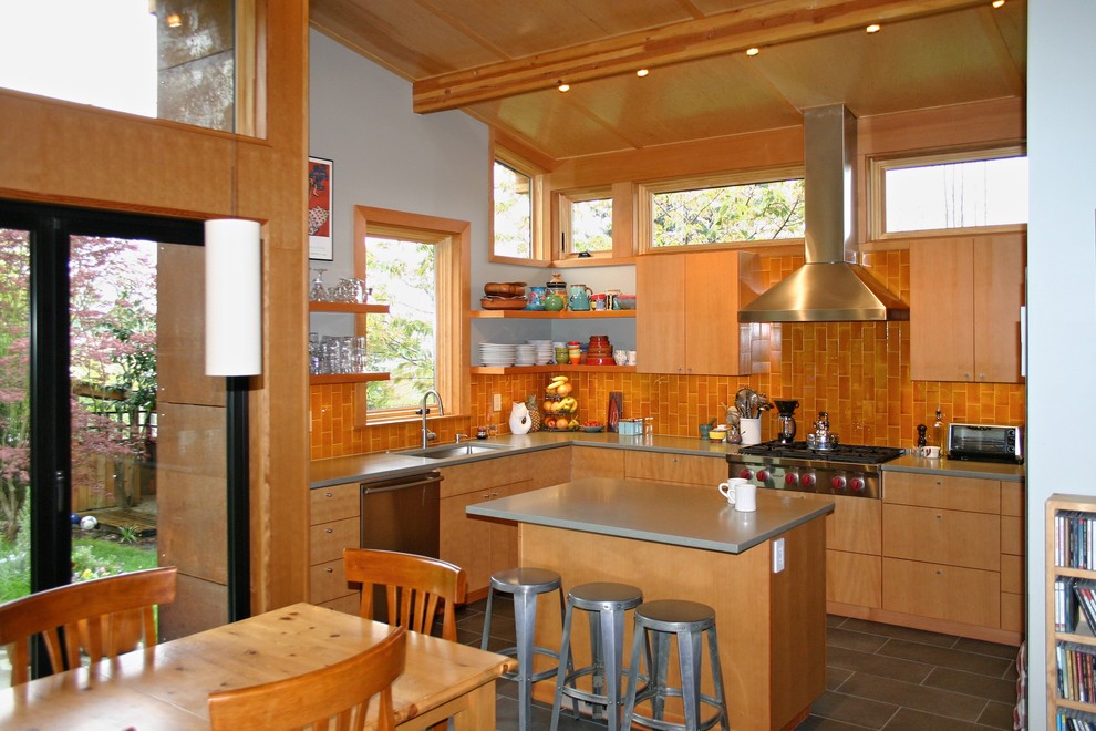 Mid-sized contemporary u-shaped eat-in kitchen in Seattle with an undermount sink, flat-panel cabinets, light wood cabinets, solid surface benchtops, orange splashback, ceramic splashback, stainless steel appliances, porcelain floors and with island.