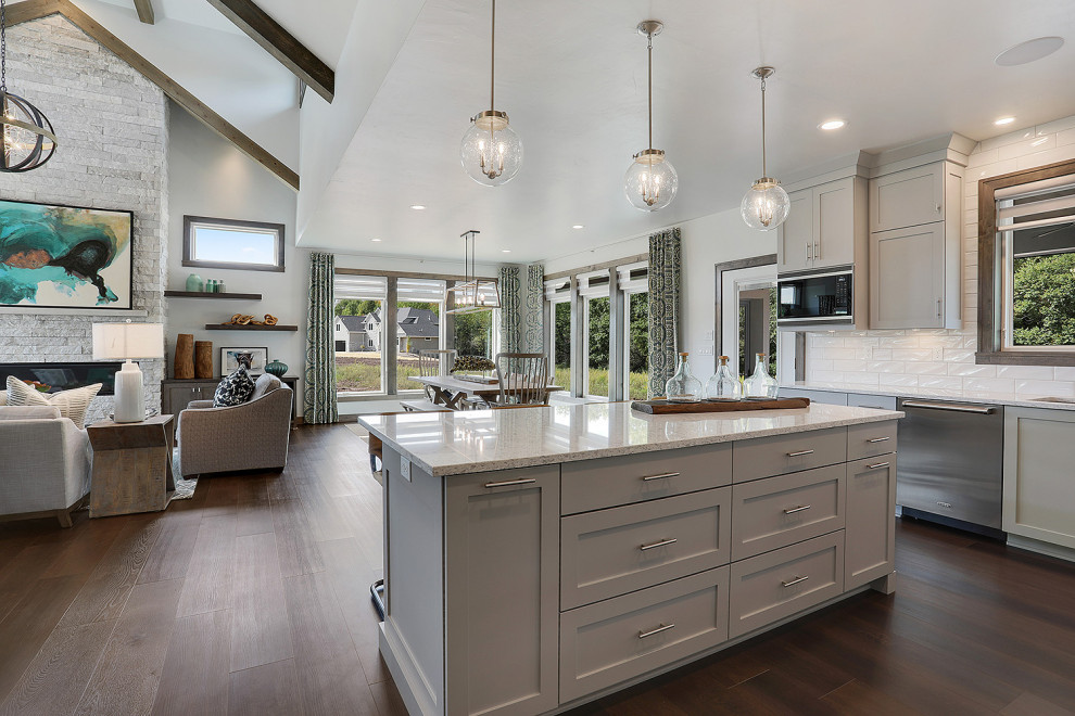 Mid-sized transitional u-shaped vinyl floor and brown floor open concept kitchen photo with an undermount sink, flat-panel cabinets, gray cabinets, quartz countertops, white backsplash, porcelain backsplash, stainless steel appliances, an island and white countertops