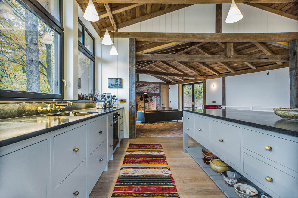 Eat-in kitchen - rustic single-wall exposed beam eat-in kitchen idea in Grand Rapids with an undermount sink, flat-panel cabinets, gray cabinets, stainless steel appliances, an island and black countertops